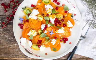 Salat mit gelben Tomaten, roten Johannisbeeren, Ziegenfrischkäse und Orangenvinaigrette